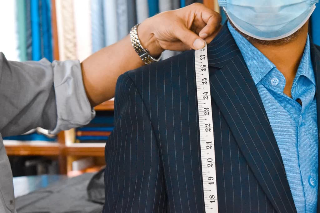 A tailor measuring a pinstripe jacket at Khimji's, Dar es Salaam